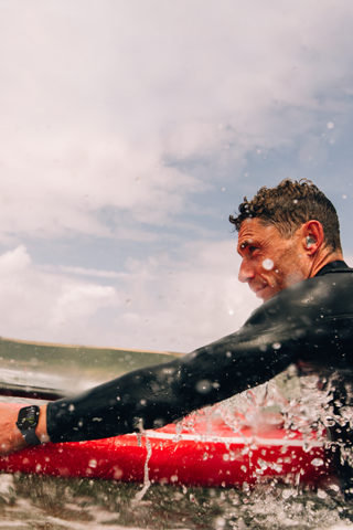 A man with a paddle board in the water wearing an AppleWatch Series10